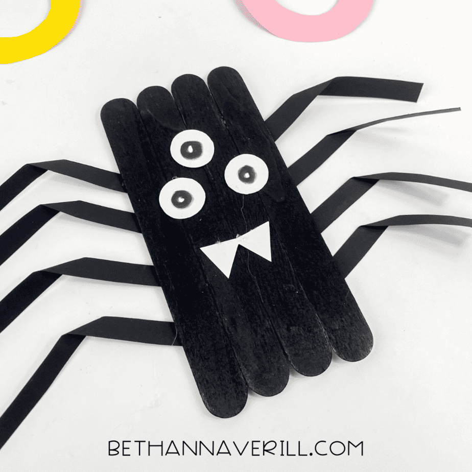 Angled close‑up of the completed popsicle stick spider showing the layered sticks and bent paper legs.