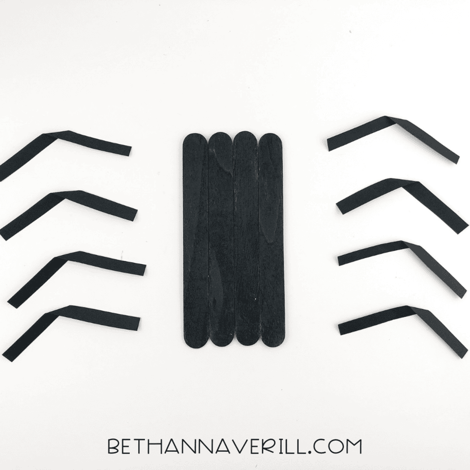 Eight paper leg strips folded to make joints, arranged around the black stick body.