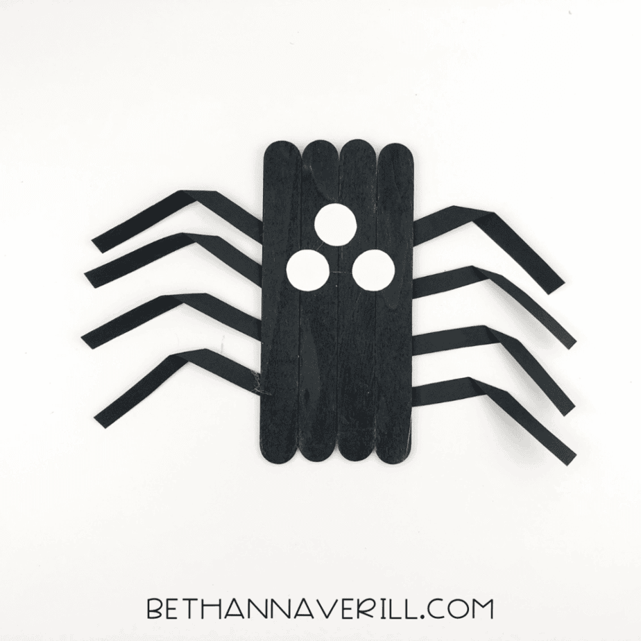 Three small white paper circles glued as eyes on the spider’s body.