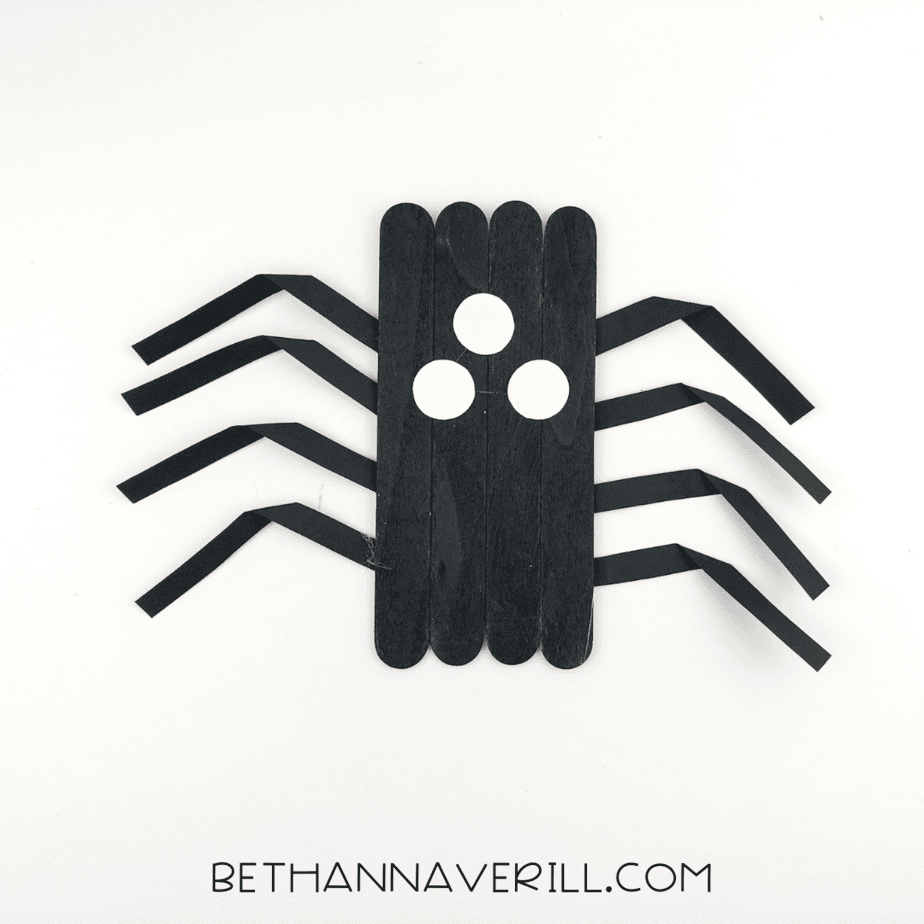 Three small white paper circles glued as eyes on the spider’s body.