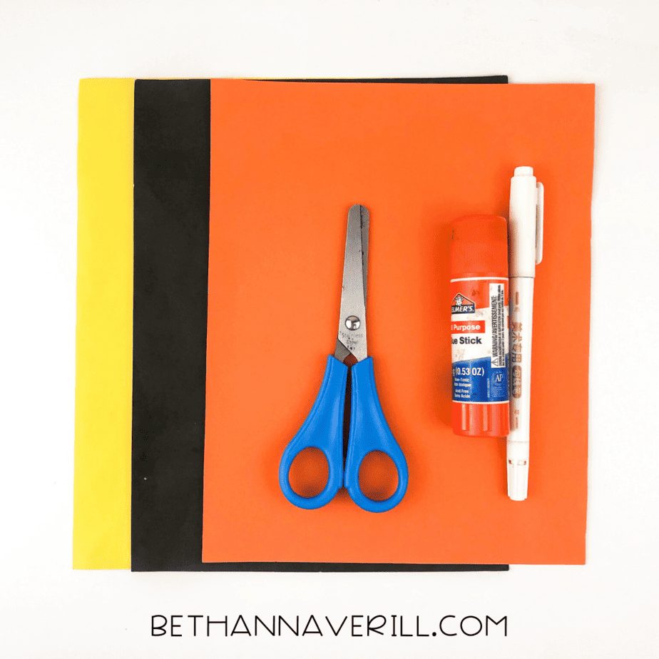 Materials for sun handprint craft: yellow, orange, black paper, scissors, glue, marker