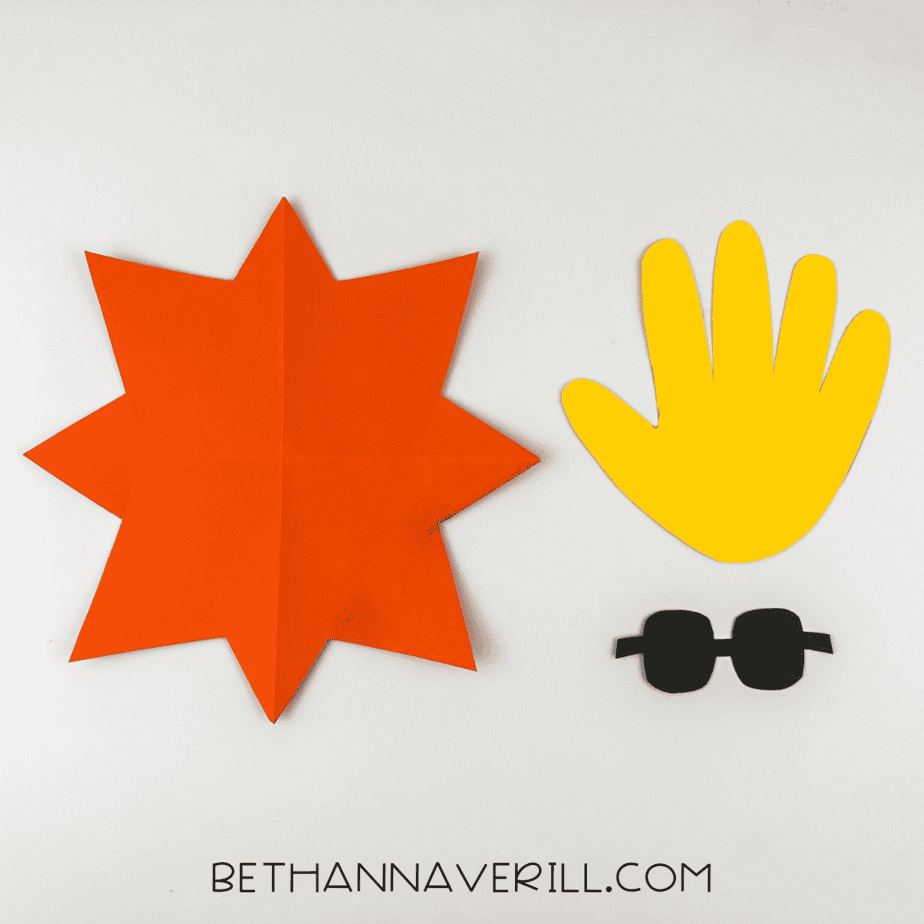 Cutout shapes: orange sunburst, yellow handprint, and black sunglasses