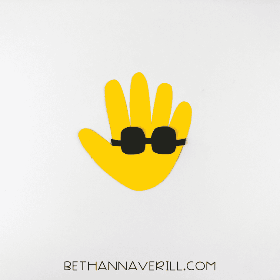 Yellow handprint with black sunglasses glued on