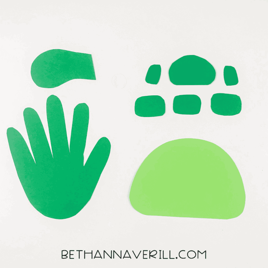 Turtle handprint craft pieces cut out from construction paper.
