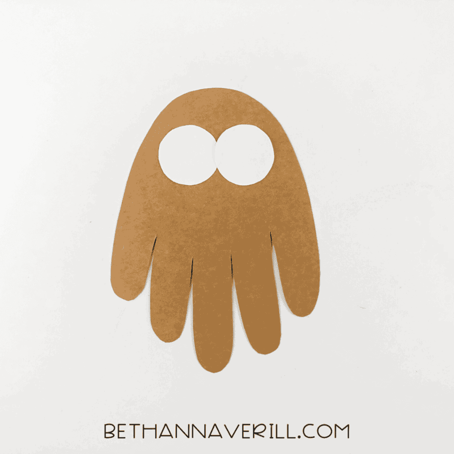 Brown handprint with two white eye circles glued on top.