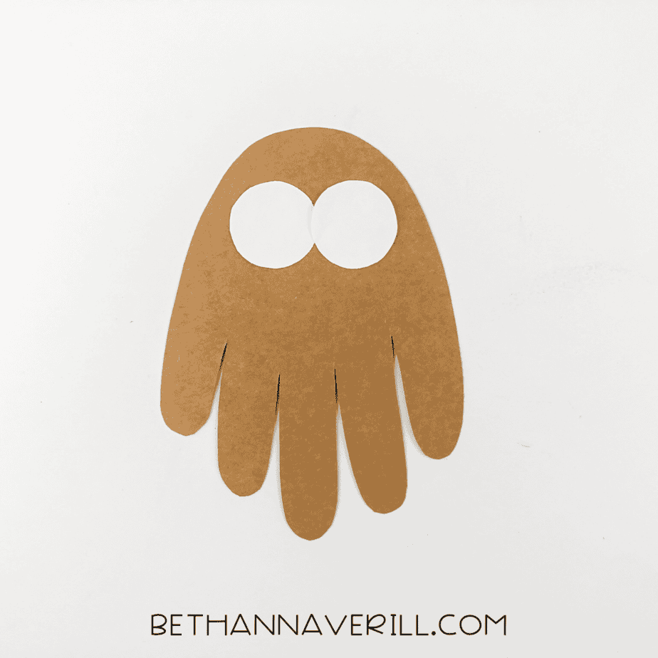 Brown handprint with two white eye circles glued on top.