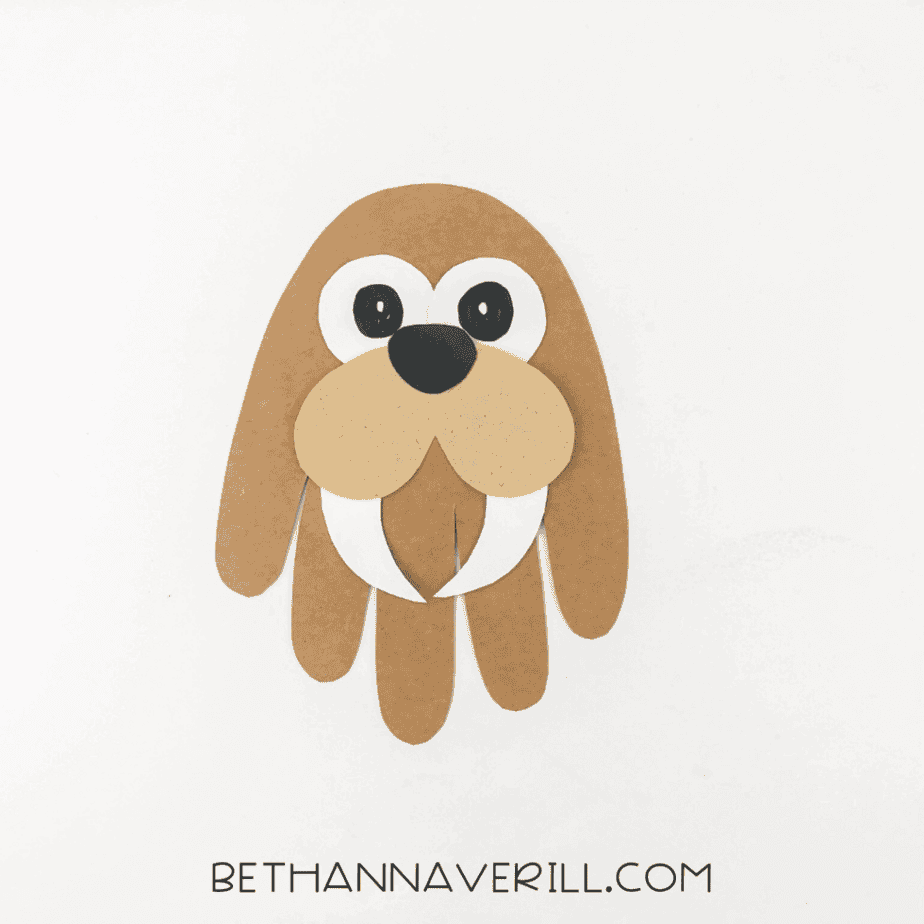 Walrus face assembled on handprint base, including eyes, cheeks, tusks, and nose.