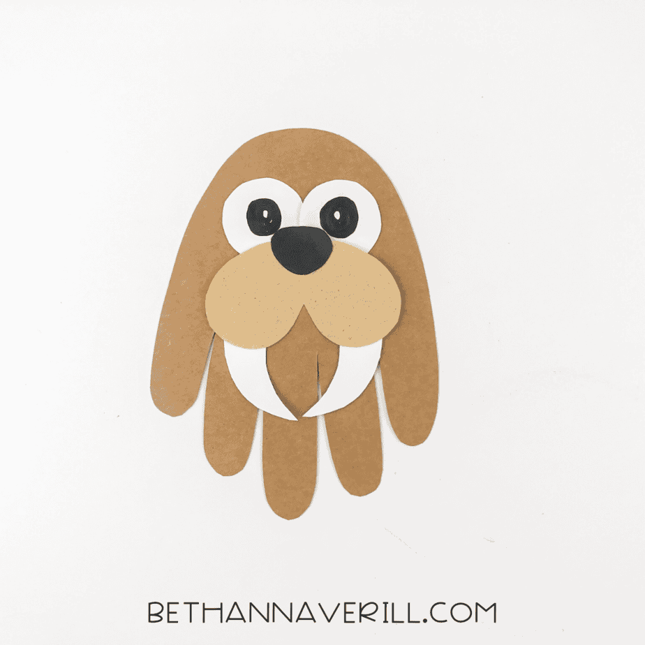 Walrus face assembled on handprint base, including eyes, cheeks, tusks, and nose.
