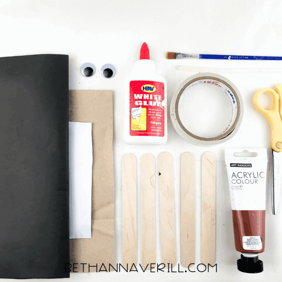 Overhead view of all craft materials including brown paint, googly eyes, glue, and construction paper.