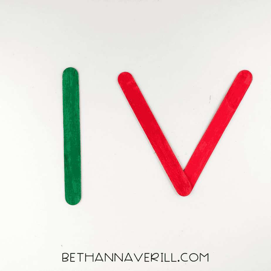 Popsicle sticks arranged in a triangle shape (red sides and green base).