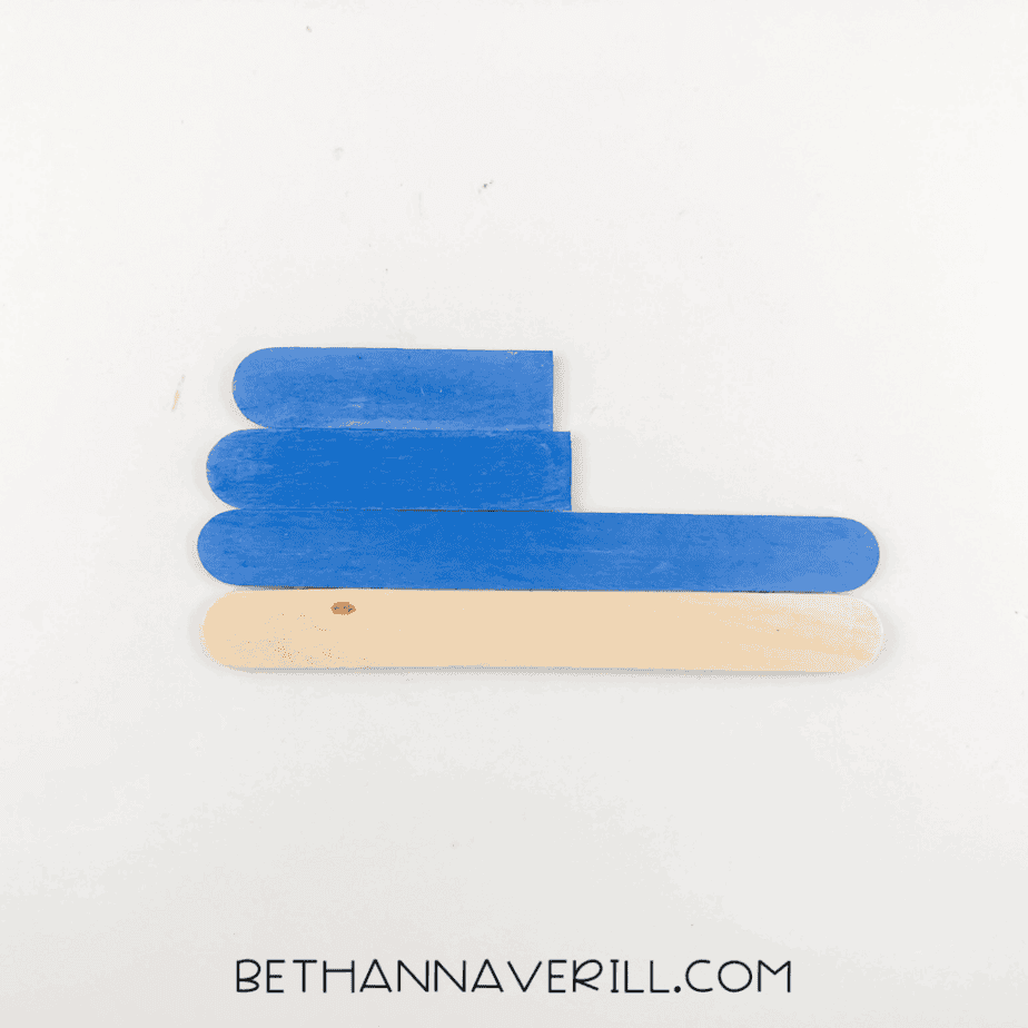 Popsicle sticks glued into a whale body shape.