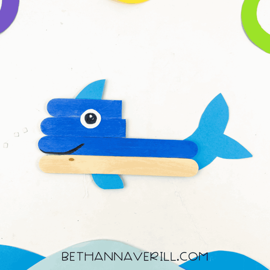 Whale on display with colorful paper sea background.