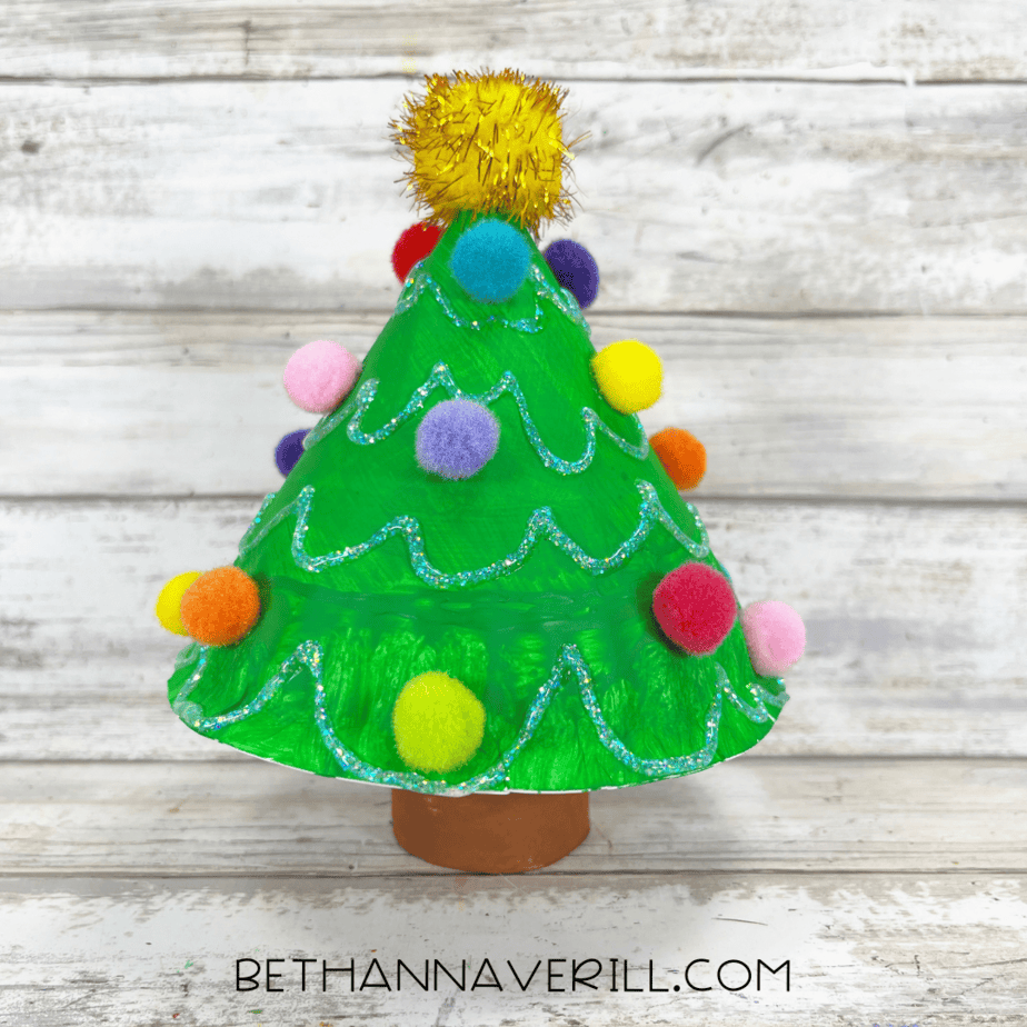 Completed 3D paper plate Christmas tree decorated with pom poms and glitter glue.