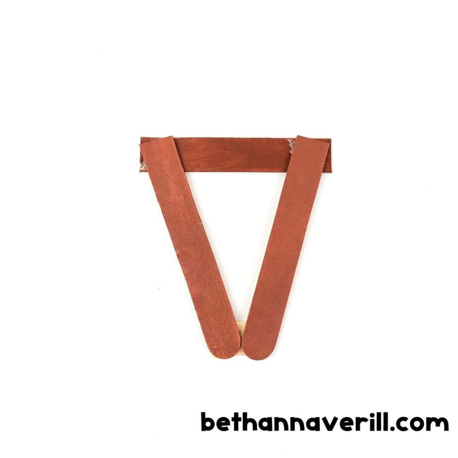 Three craft sticks painted brown and glued into a triangle shape to form the base of the reindeer’s face.