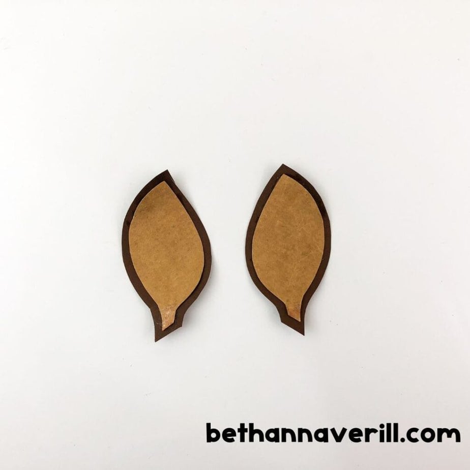 Two tan ear shapes now glued onto slightly larger brown paper cutouts to create a layered ear effect.