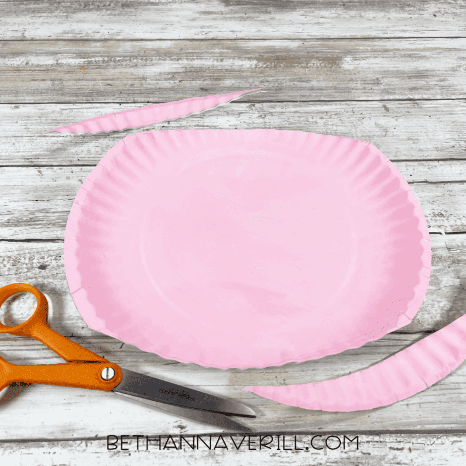 Painted paper plate with edges trimmed off using scissors.