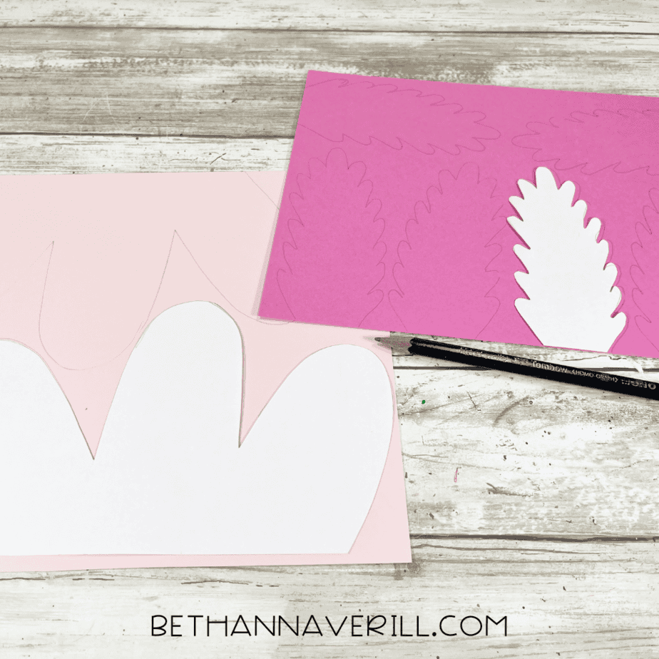 Pink paper traced with axolotl gill shapes next to templates.