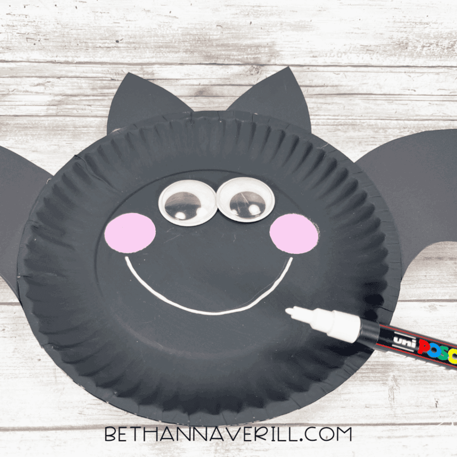 Front of bat craft with white paint marker drawing a big smile under the eyes and cheeks.
