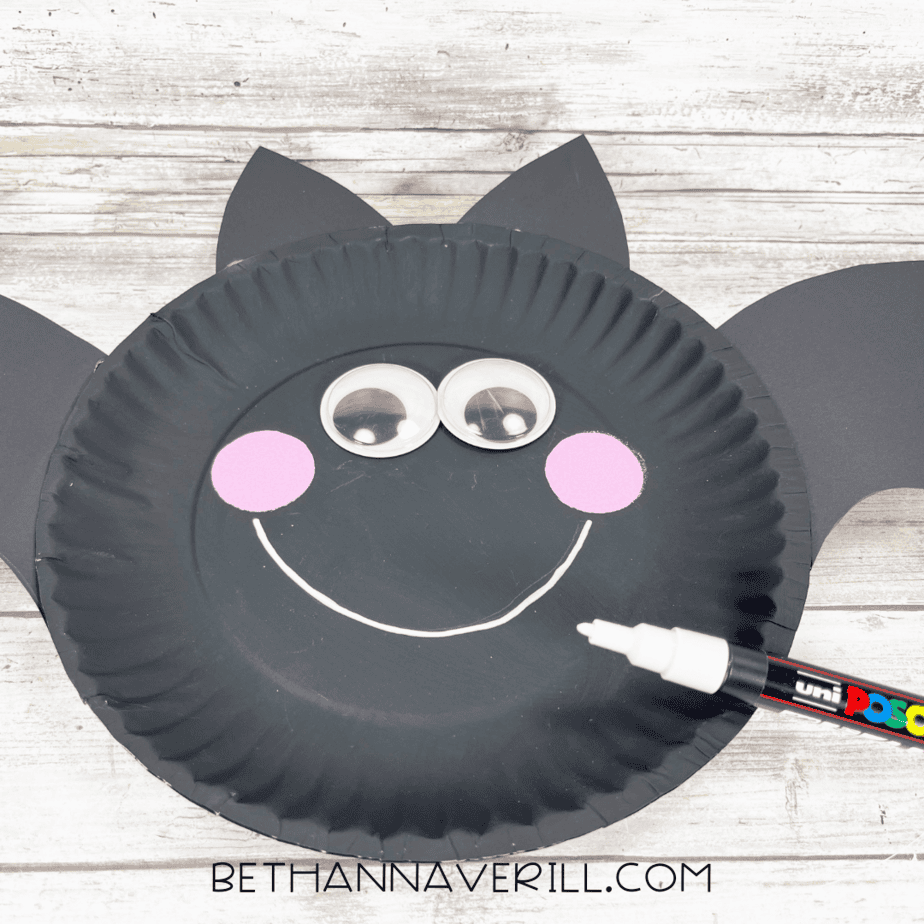Front of bat craft with white paint marker drawing a big smile under the eyes and cheeks.