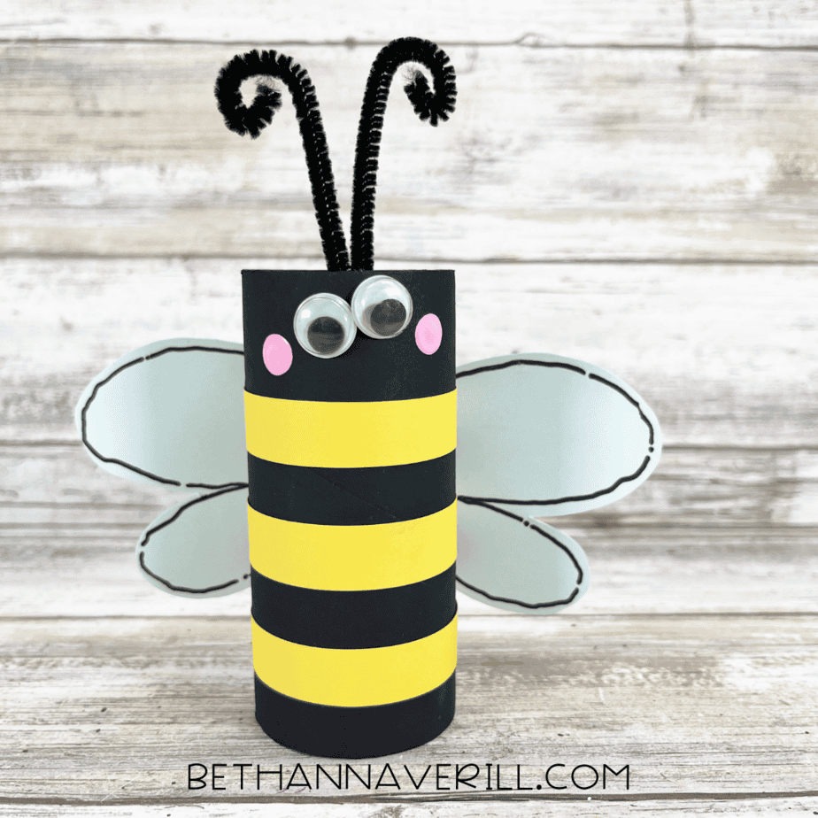 Finished toilet paper roll bee craft with wings, stripes, googly eyes, antennae, and cheeks.