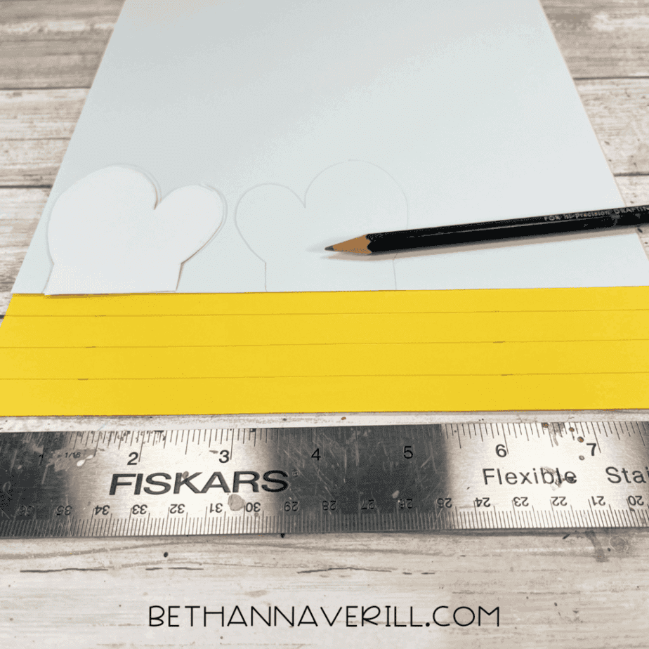 White and yellow paper with bee wings and stripe templates drawn on, pencil and ruler nearby.