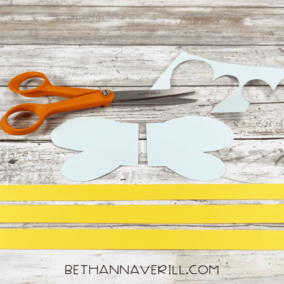 Cut-out bee wings and yellow stripes next to scissors.