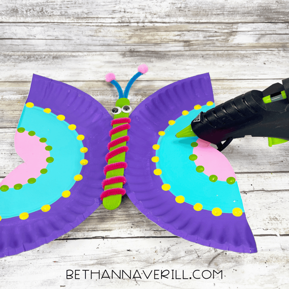 Paper plate wings glued to the decorated craft stick body.