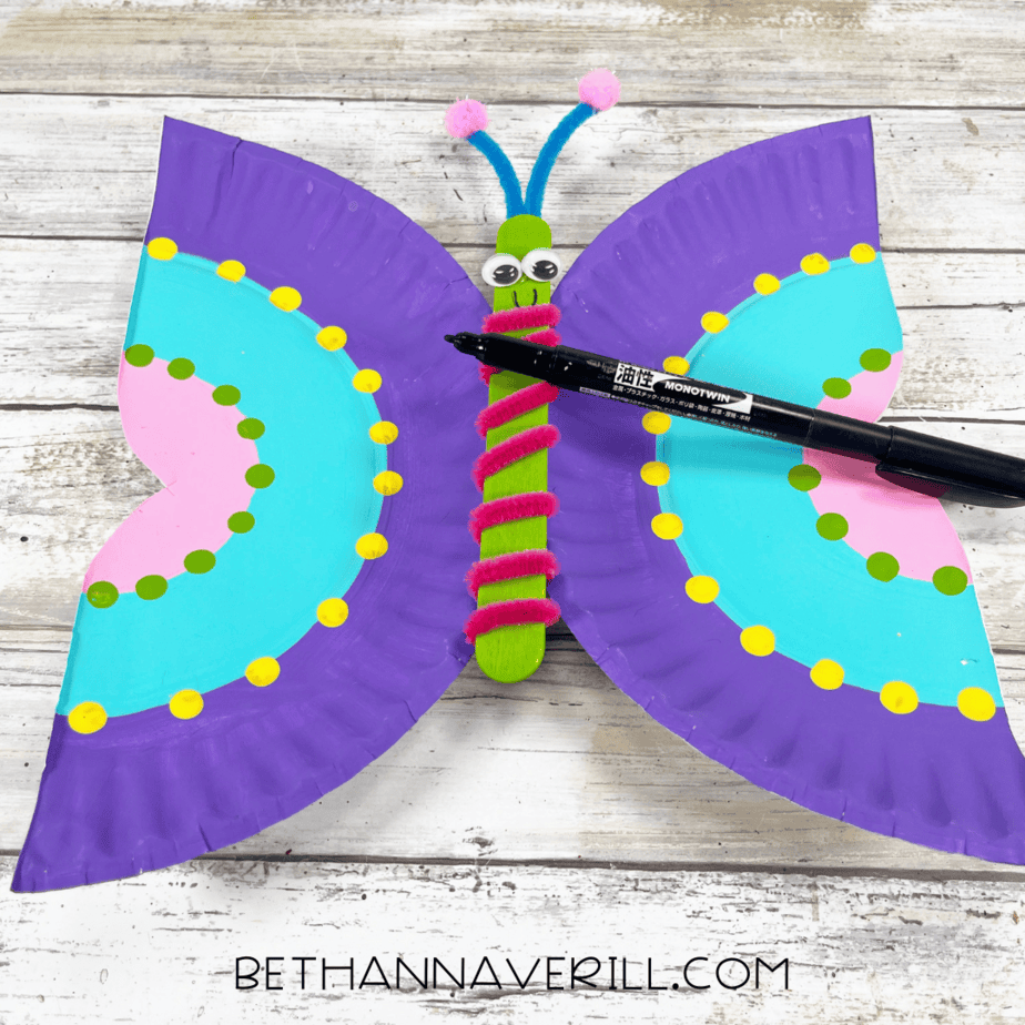 black marker adding smile to butterfly paper plate
