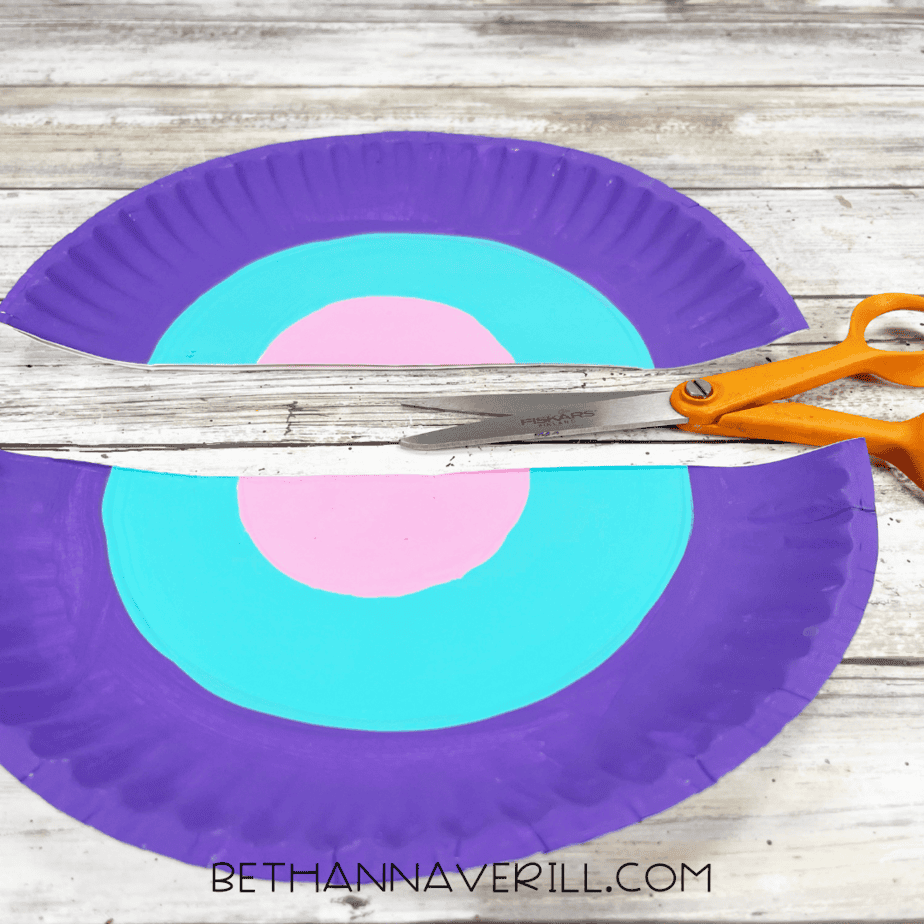 Painted paper plate cut in half with scissors.