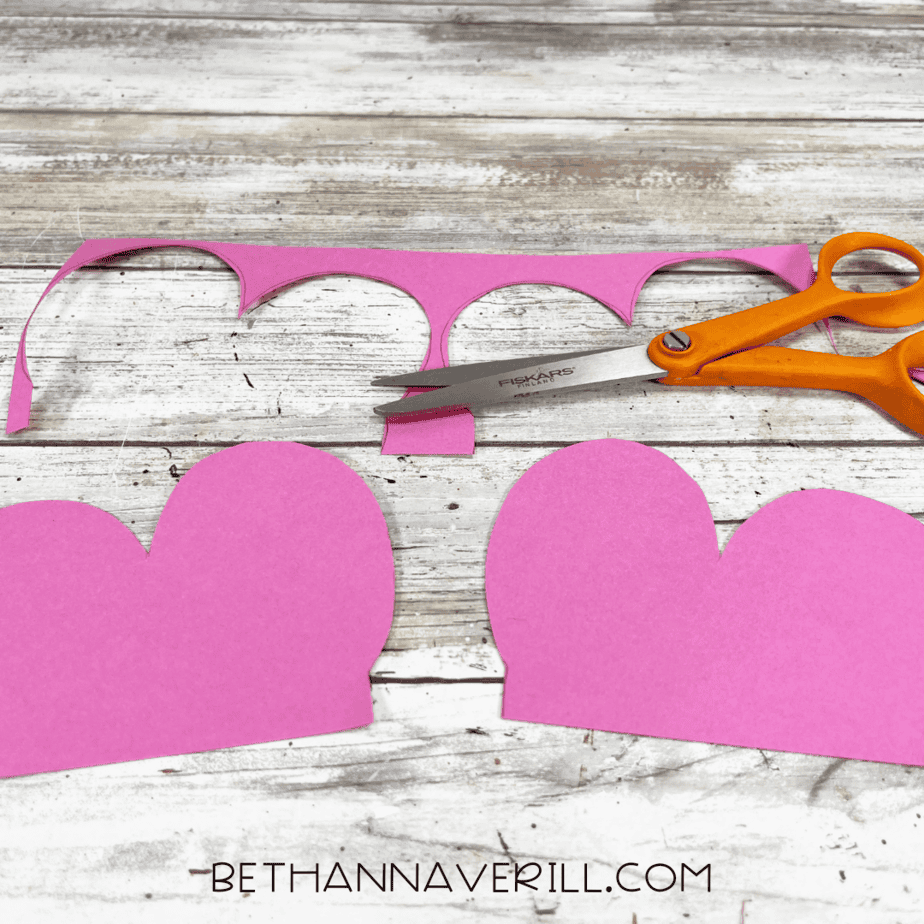 Cut-out pink butterfly wings on the table with scissors.