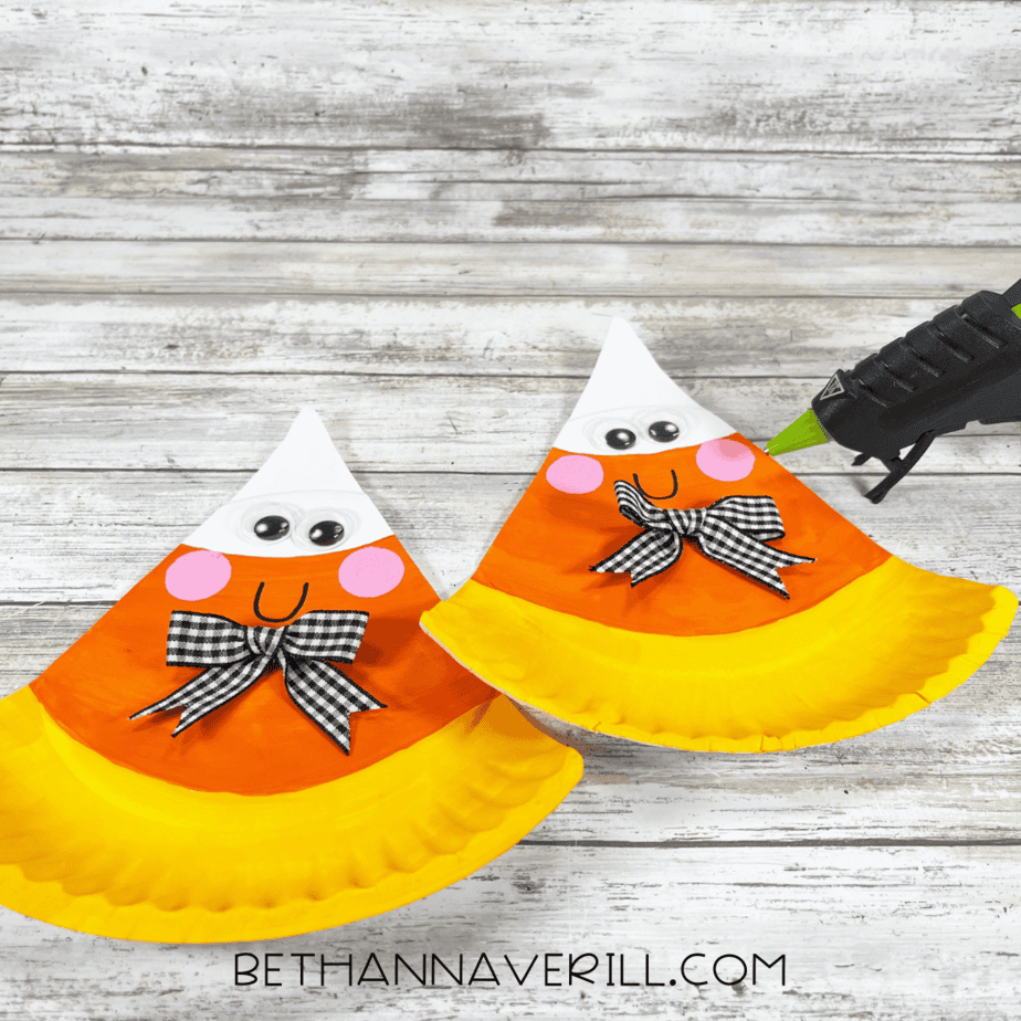 Candy corn crafts with bows glued below their smiles.