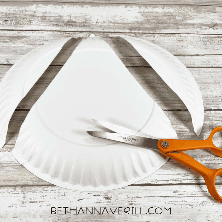 Paper plate cut into a candy corn shape using scissors.