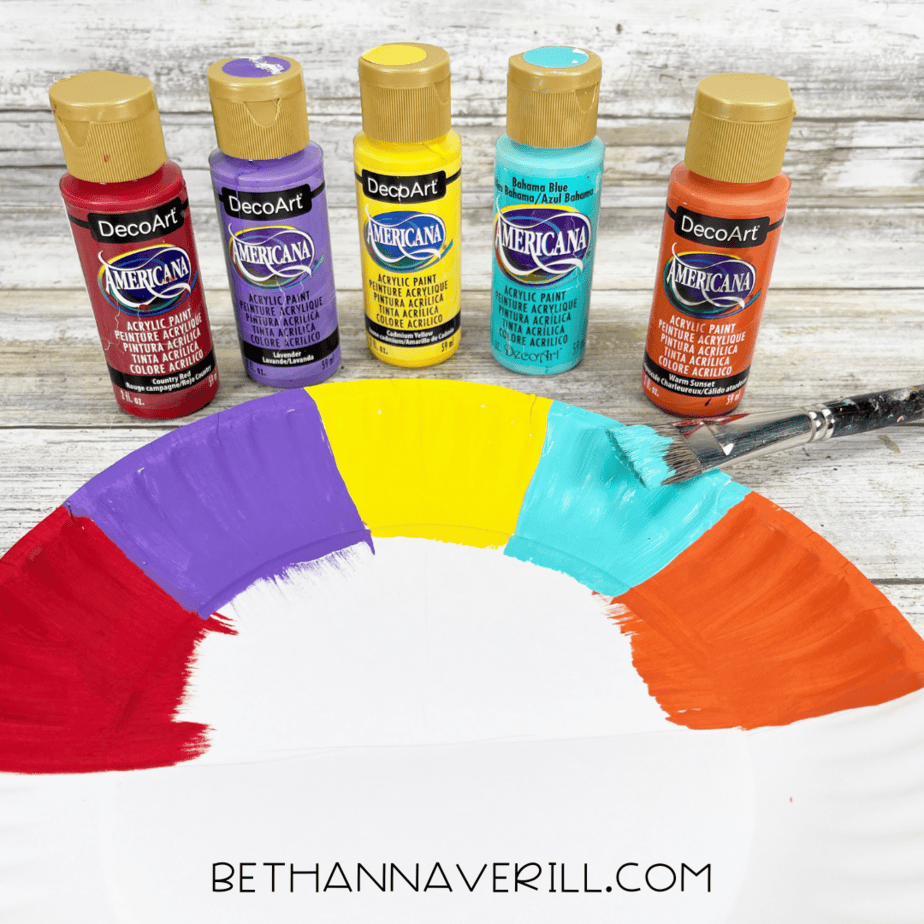 Paper plate painted in rainbow sections of red, purple, yellow, teal, and orange.