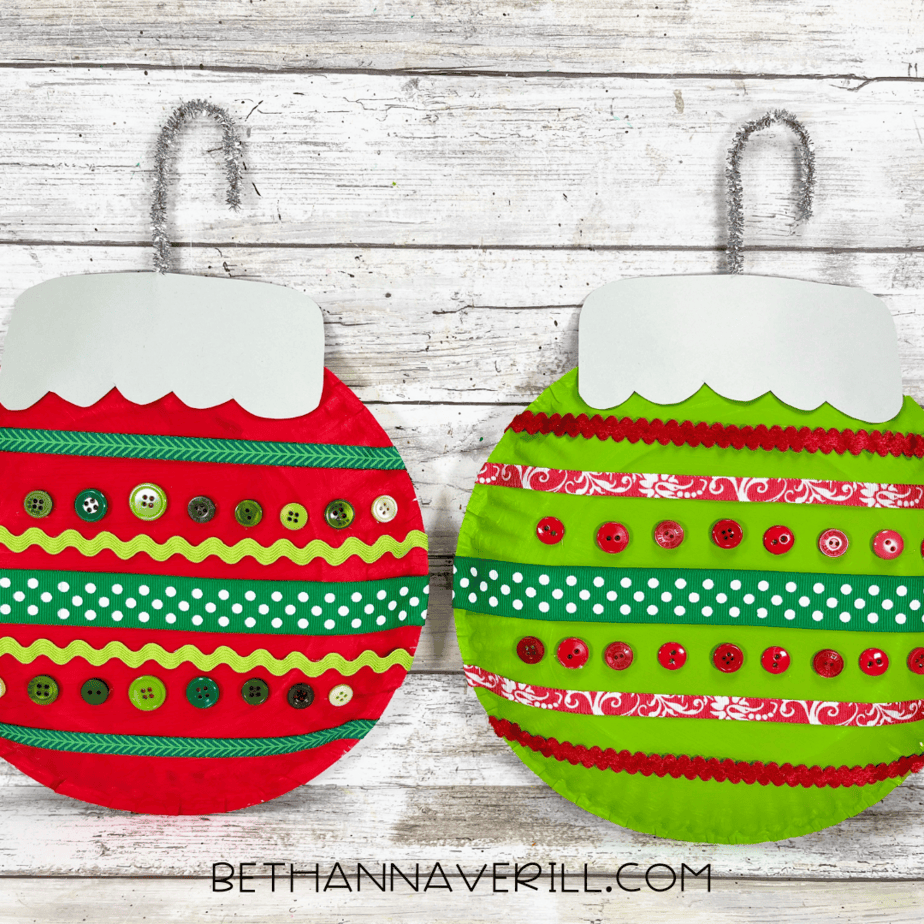 Finished red and green Christmas ornament paper plate crafts decorated with ribbons and buttons.