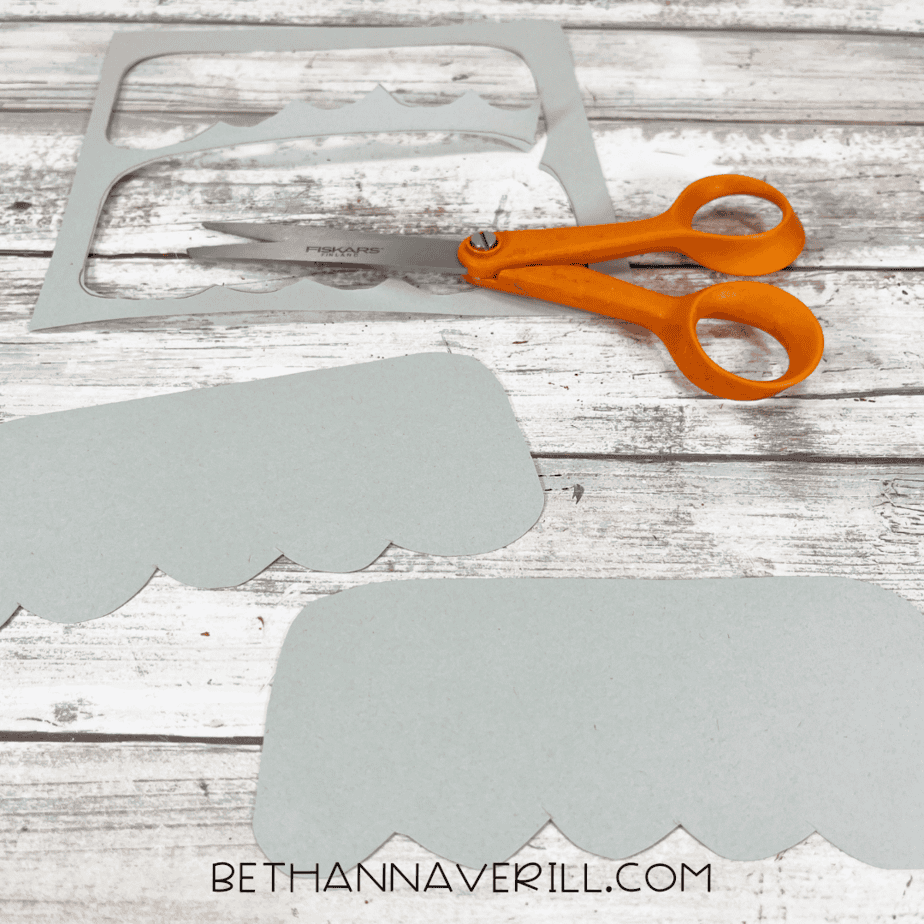 Cut-out ornament tops with scalloped edges next to orange scissors.