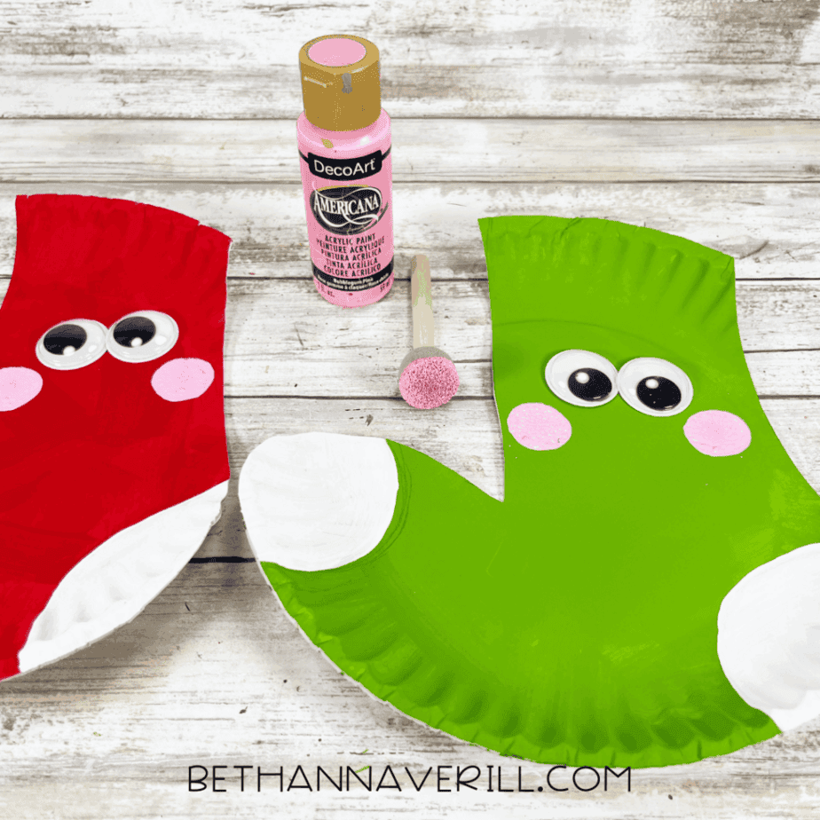 Red and green paper plate stockings with pink painted cheeks added under the eyes.