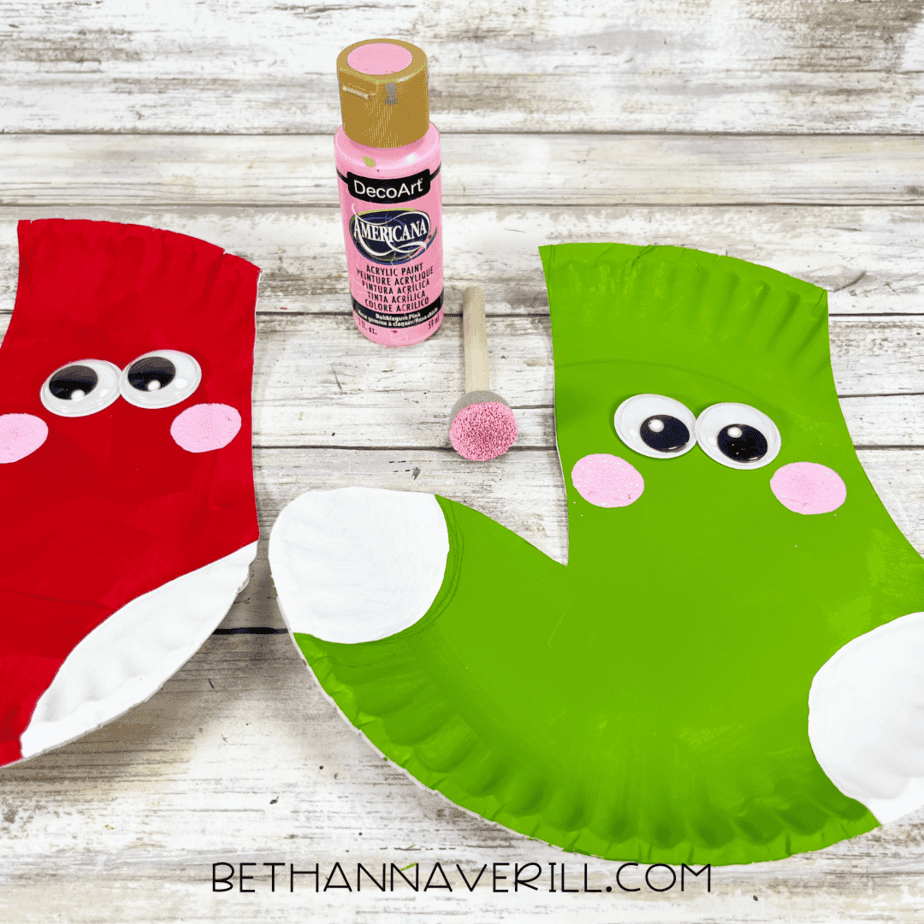Red and green paper plate stockings with pink painted cheeks added under the eyes.