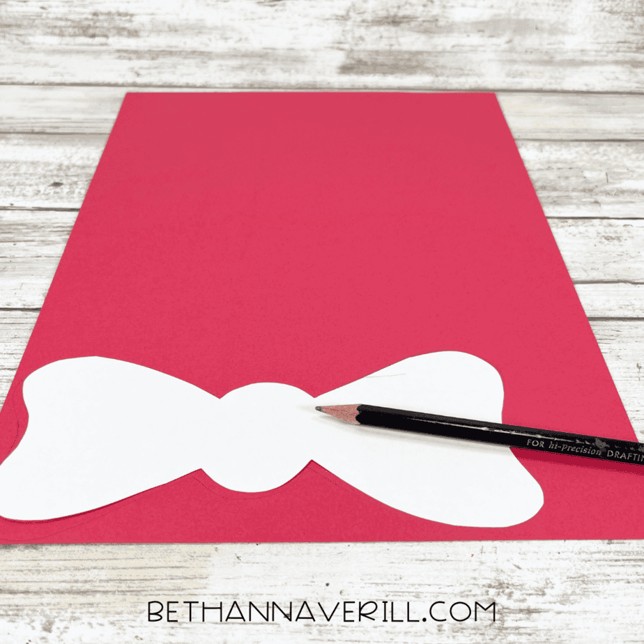 Bow template traced onto red construction paper with a pencil.