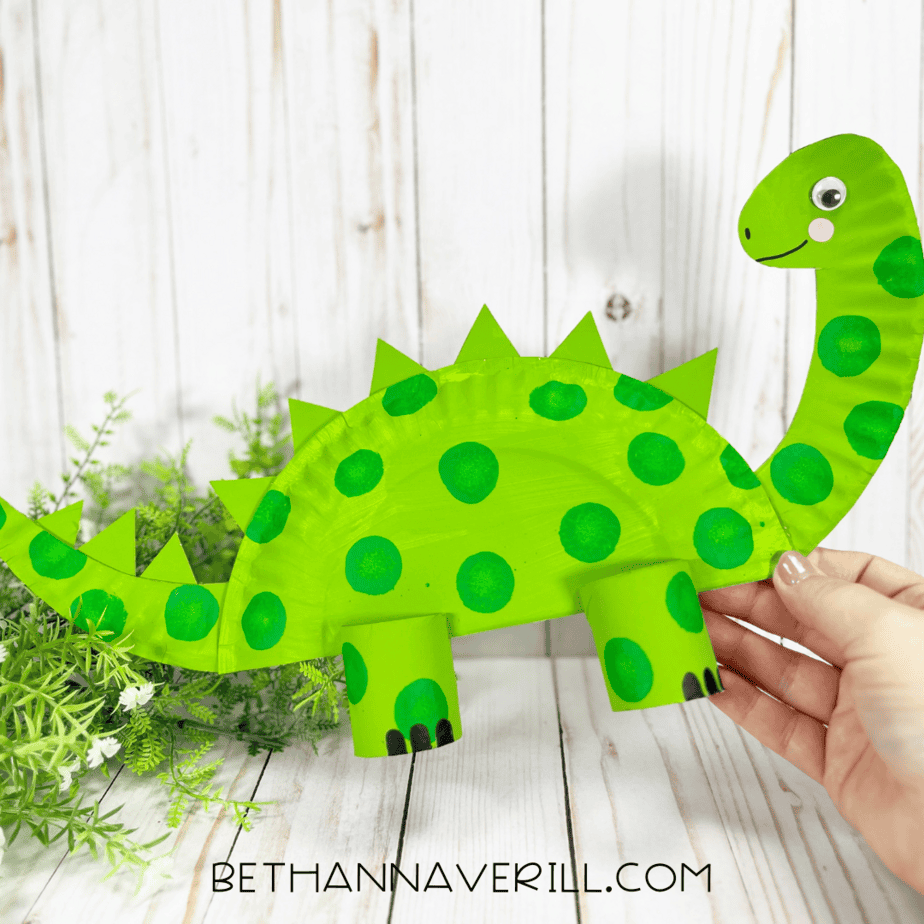 Finished dinosaur craft being held up against a light background.