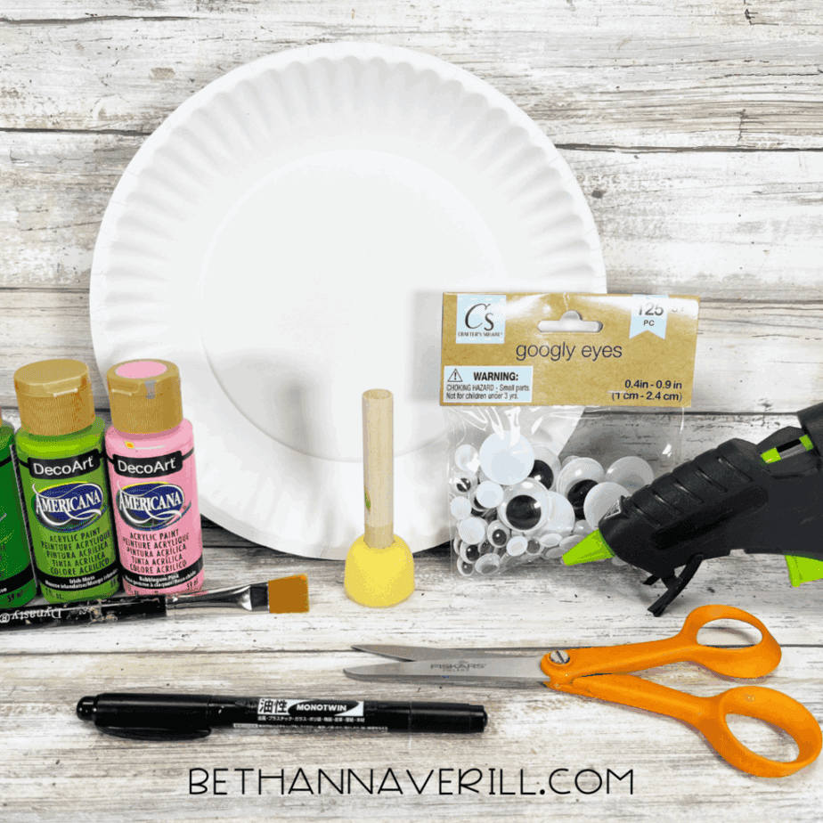 Craft supplies including paints, googly eyes, paper plate, scissors, glue gun, and marker.