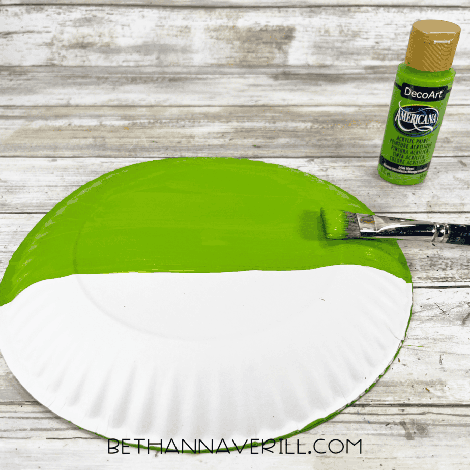 Back of paper plate half painted green.