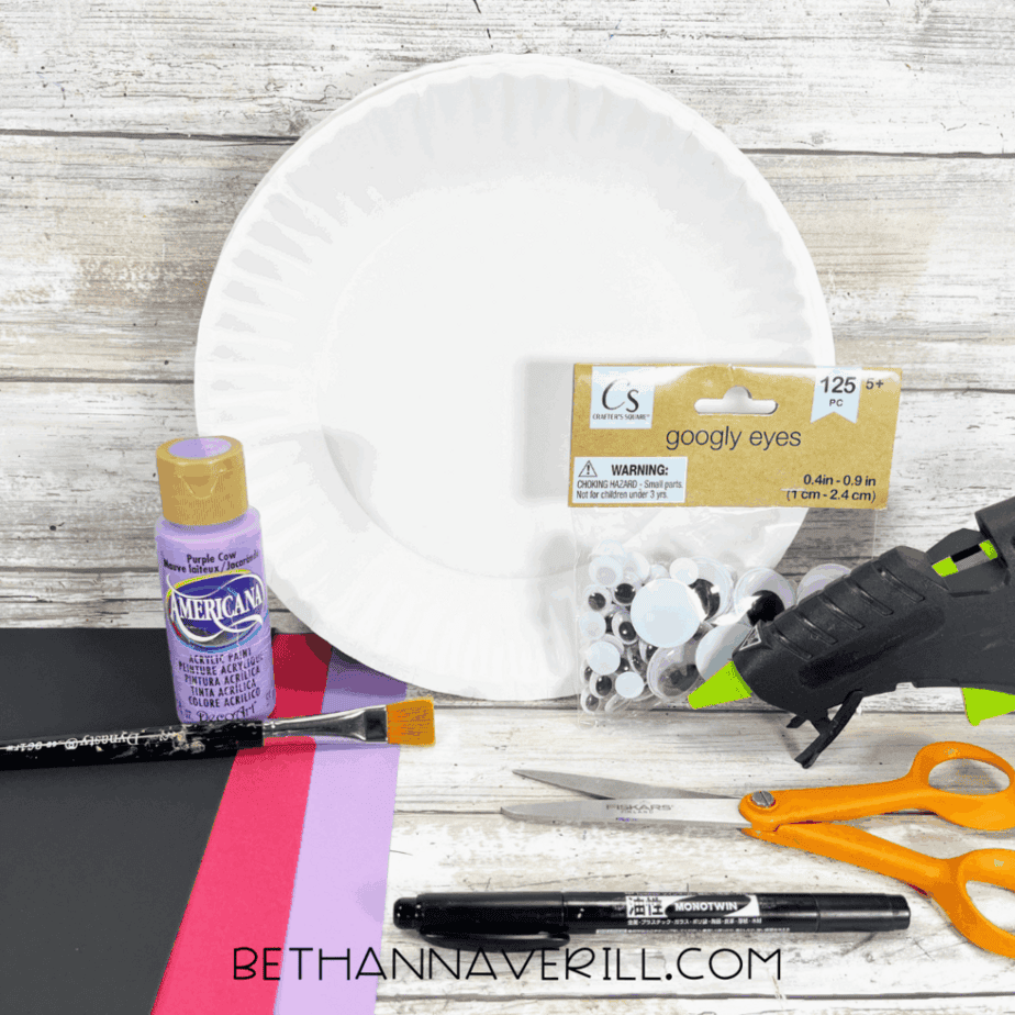 Dracula paper plate craft supplies including a paper plate, purple paint, construction paper, and googly eyes