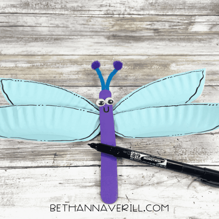 Dragonfly assembled with wings attached to the purple body, a black marker adding a smile.