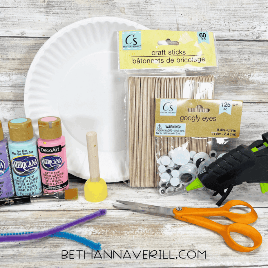 Craft supplies including paint, paper plate, craft sticks, googly eyes, scissors, pipe cleaners, and glue gun.