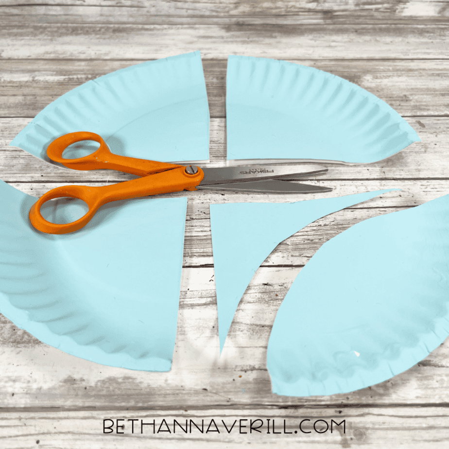 Painted paper plate cut into four equal wing-shaped sections with scissors.
