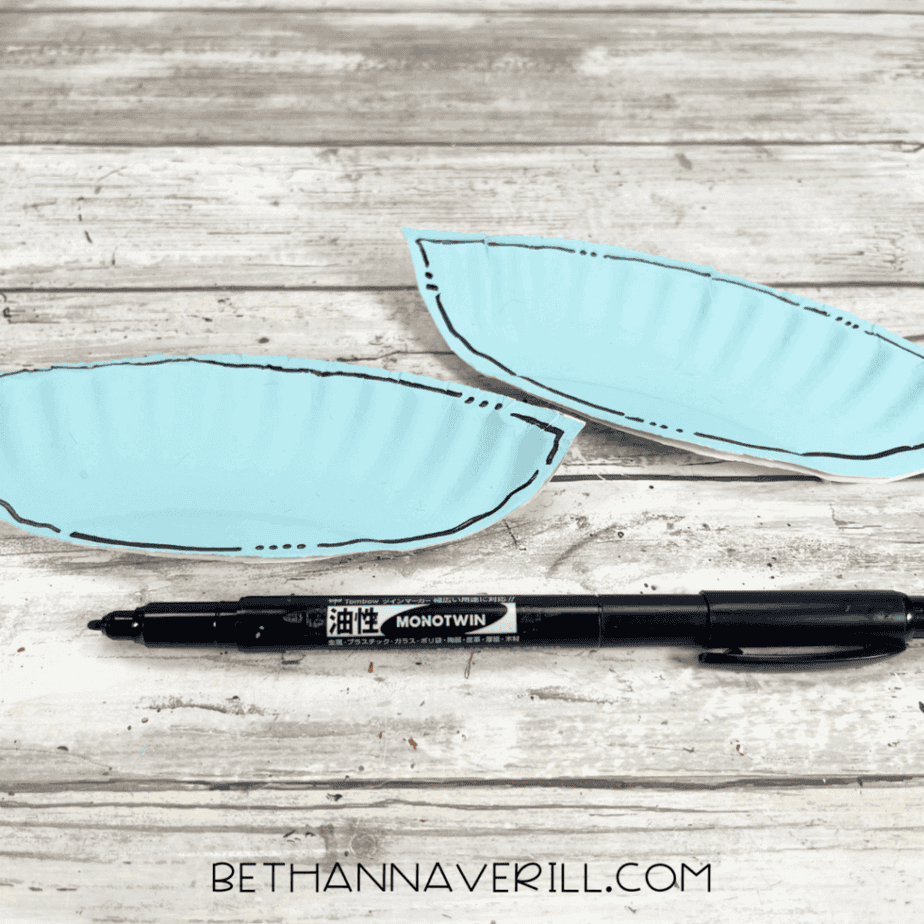 Two blue paper plate wings outlined with a black marker.
