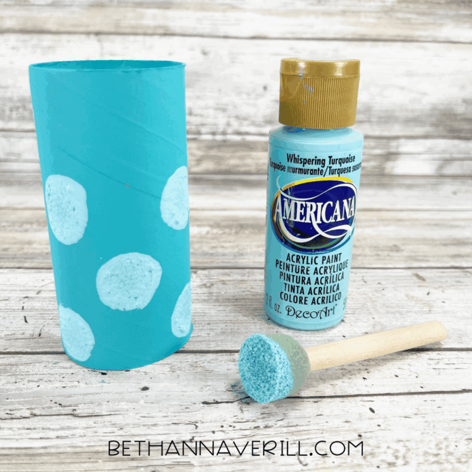 Aqua painted toilet paper roll decorated with light blue polka dots using a sponge dabber.