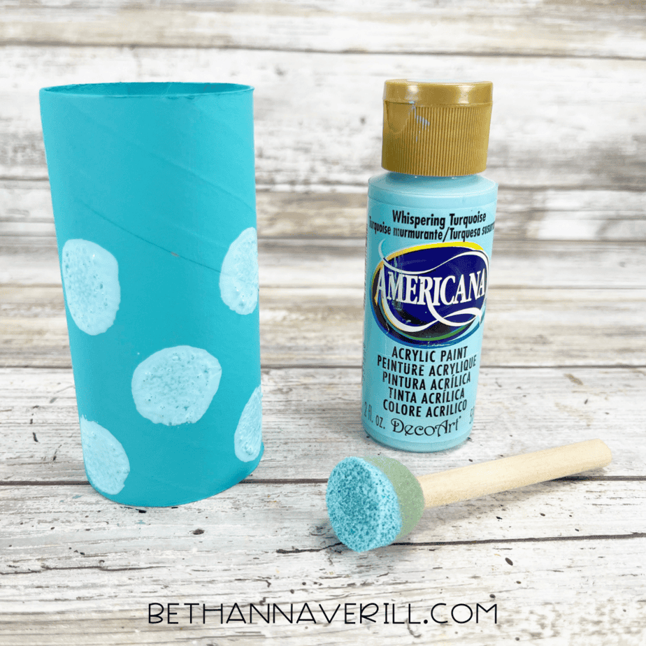 Aqua painted toilet paper roll decorated with light blue polka dots using a sponge dabber.