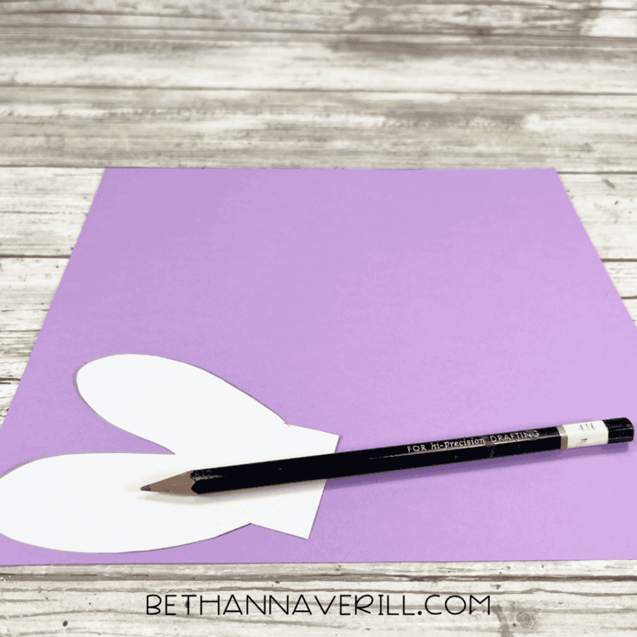 Dragonfly wing template traced onto purple construction paper with a pencil.