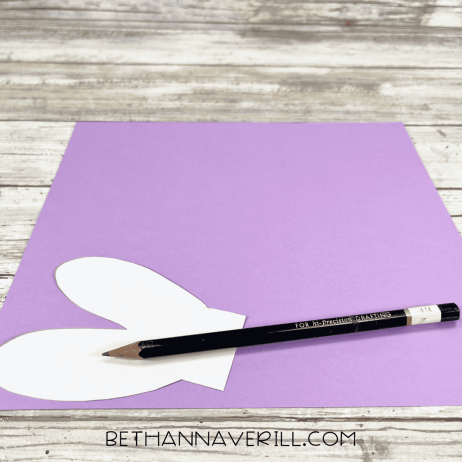 Dragonfly wing template traced onto purple construction paper with a pencil.